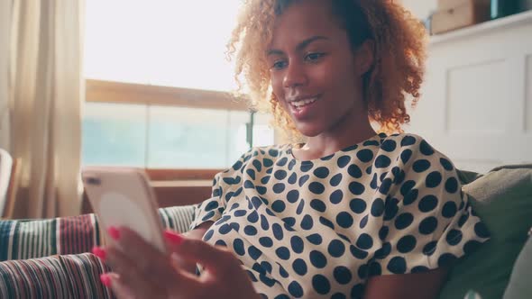 Young African American Woman Making Video Call on Phone Sits in Living Room alt