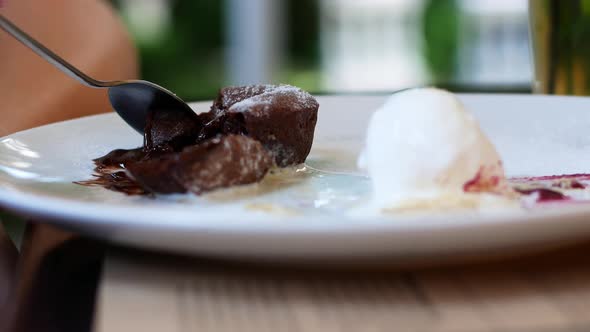 Women eating chocolate cake in a summer cafe. Liquid chocolate flows smoothly out of the cake alt