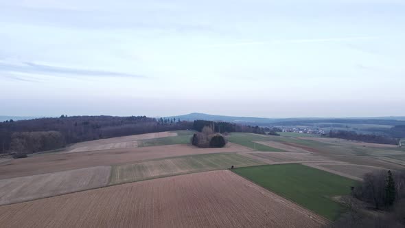 Fields and meadows bordering at bare mixed forests in Hesse, Germany. Aerial tracking shot alt