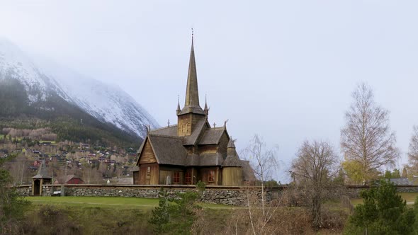 Traditional Wooden Church At Lom Stavkyrkje With Stoned Wall Fence In Norway. Aerial Ascending alt