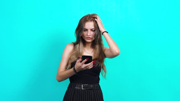 The Puzzled Young Woman Receives a Message on the Phone and Is Saddened. alt