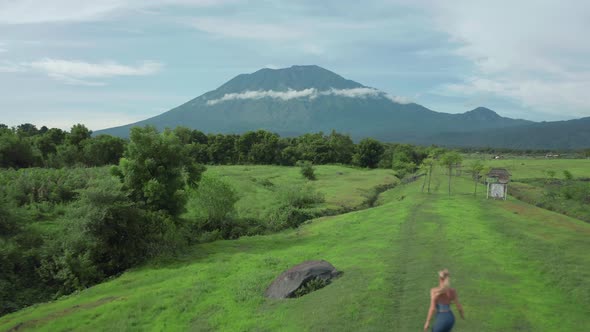 Female adventure traveler runs barefoot onto rock celebrating epic view, Bali alt