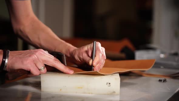 Close Up Shot of an Employee's Hands, Who Makes Holes with a Hammer in a Eather