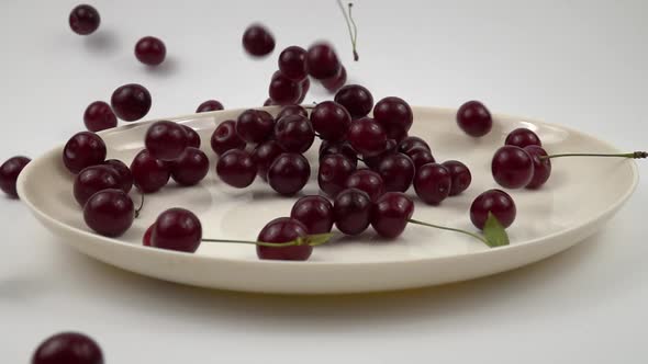 Ripe red cherries are laid out onto a white dish