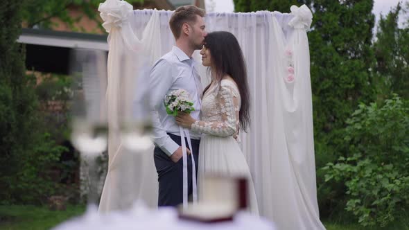Confident Loving Interracial Couple Kissing Rubbing Noses Standing at Wedding Altar in Spring Garden alt