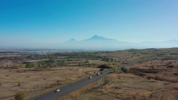 Aerial Drone Shot of Fields and Car Road on Background of Ararat Mountains alt