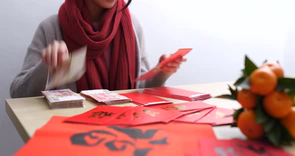 Woman putting money into red packet for lunar new year  alt