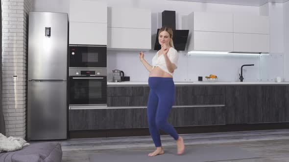Pregnant Woman with a Big Tummy Dancing to Music in Her Living Room on a Fitness Mat Happy Pregnancy