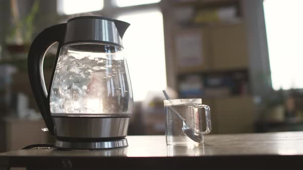 Slider Shot of a Transparent Kettle with Water Boils alt