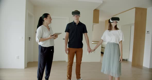 Estate Agent With Couple Wearing VR Headsets in New Apartment