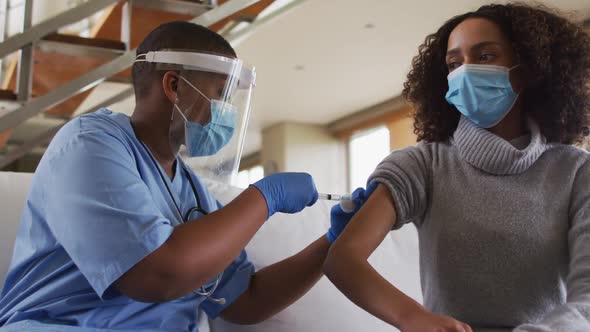 African american female doctor wearing face mask vaccinating african american patient alt