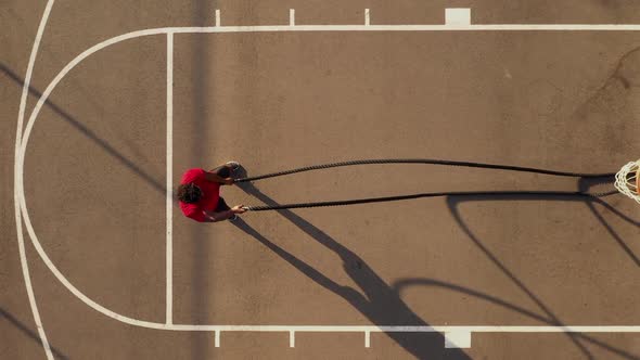 Aerial shot of a man working out with battle ropes alt