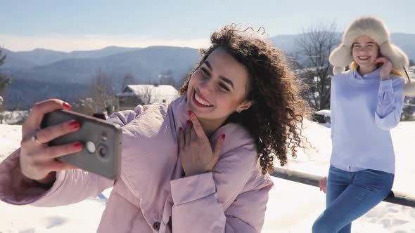 Girls Friends Making Mobile Photo at Snowy Mountain Landscape alt