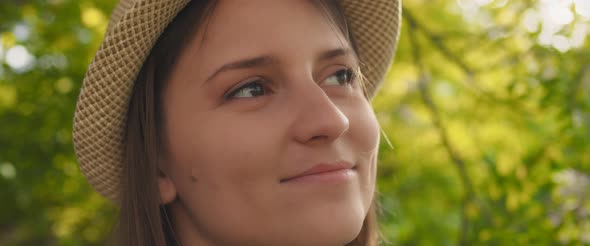 Close up of a woman with hat looking away, with light breeze blowing on her face alt