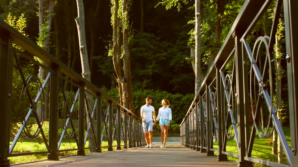 Guy and a Girl Walking on a Bridge in the Park alt