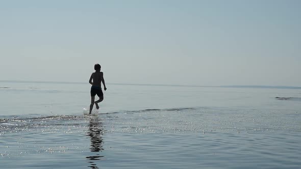 Teen Boy Running Along the Sea Beach