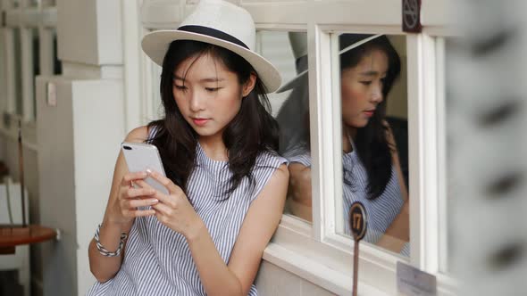 Beautiful Asian girl using smartphone at a coffee shop.