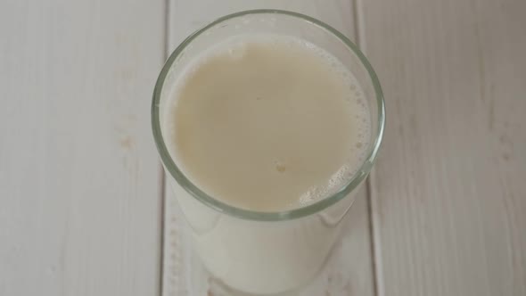A Full Glass of Milk on a Light Background Drops of Milk Fall Into the Glass alt
