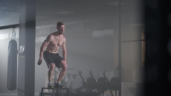 Slow Motion Muscular Shirtless Fit Man Energetically Box Jumps in Hardcore Gym Doing Part of His alt