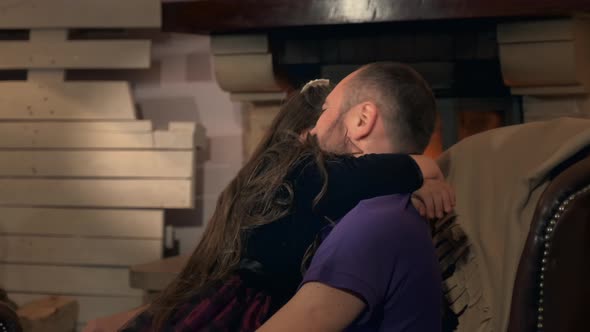 Happy Dad Have Fun with His Daughter Sitting on Comfortable Armchair with Fireplace alt
