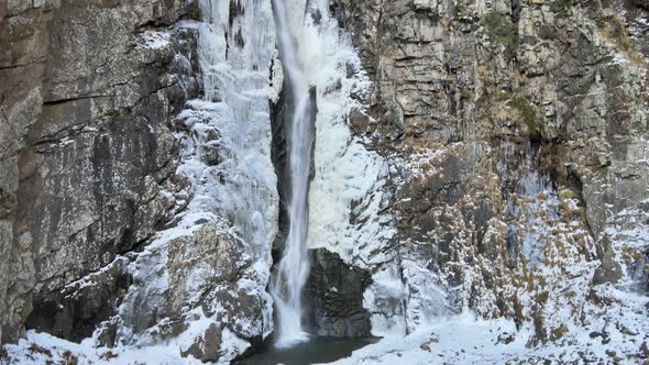 Aerial View of Gveleti Narrow Mountain Waterfall Surrounded By Rocks and Snow