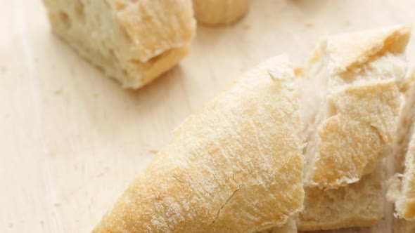 Baguette French bread on table smaller pieces cuts 4K 2160p 30fps UltraHD tilting footage - Slow til alt