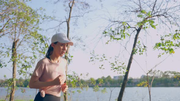 Asian young beautiful sport woman running on street in public park. alt