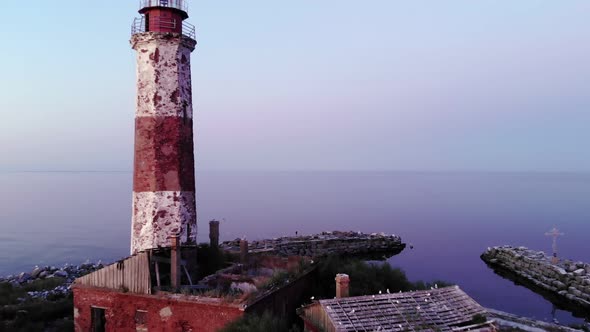 Cinematic aerial shot of small island with old lighthouse, camera fly back alt