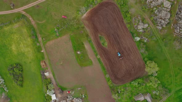 Aerial View of a Tractor Planting a Field on a Small Plot of Fertile Land alt