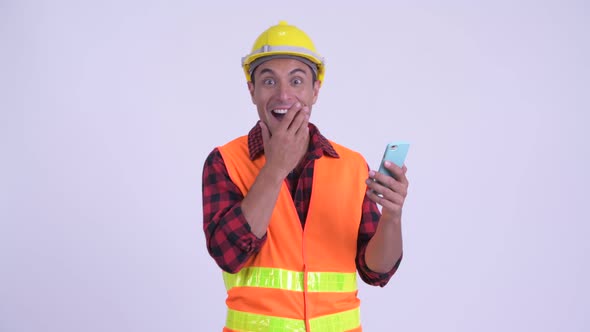 Young Happy Hispanic Man Construction Worker Using Phone and Looking Surprised