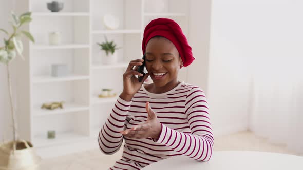 Happy Black Woman Wearing Headwrap Talking On Cellphone At Home alt