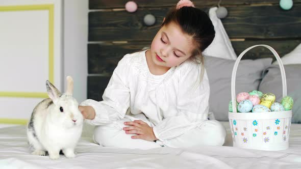 Cute girl having fun with rabbit in easter morning alt