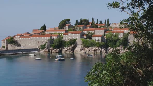 Calm Blue Sea and Moored Boats Near the Island of Sveti Stefan in Montenegro alt