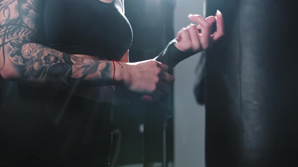 Tattooed Woman Binding Her Hands Before Box Training alt