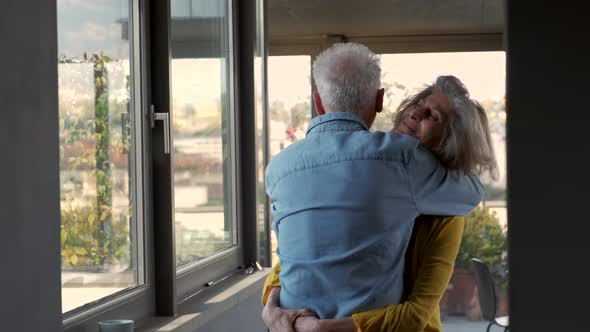 Happy senior couple embracing at home alt