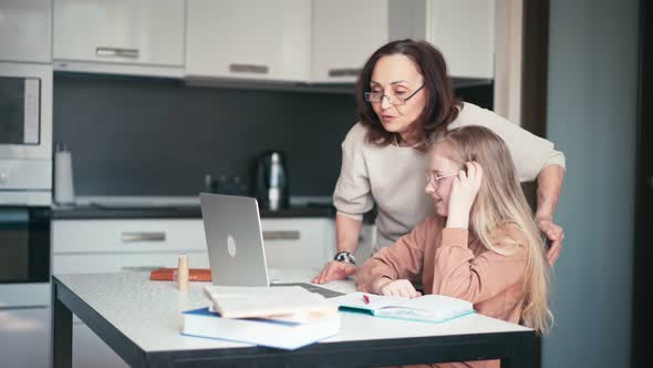 A Kind Grandmother in Eyeglasses Helping Her Granddaughter with Her Homework alt