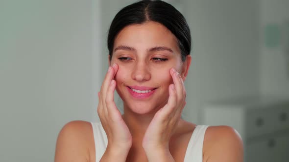 A Young Brunette Girl Massages Her Face with Her Hands in Slow Circular Movements