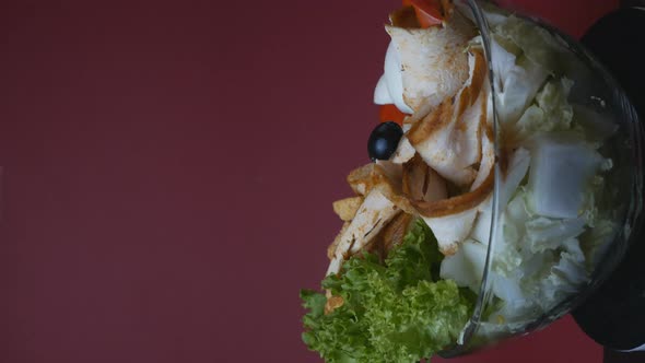 Vegetable Salad with Witch and Eggs in a Rotating Glass Plate on a Burgundy Background alt