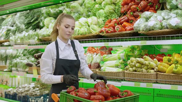 Female Puts Red Pepper on a Shelf in an Organic Store Young Woman Replenishes Products on the alt