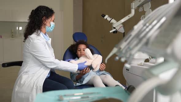 Female Stomatologist Giving Toy and Five to Child alt