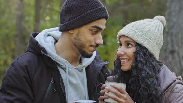 Young Happy Hispanic Couple in Love Closeup Standing Hugging Outdoors in Cold Weather Drinking Hot alt