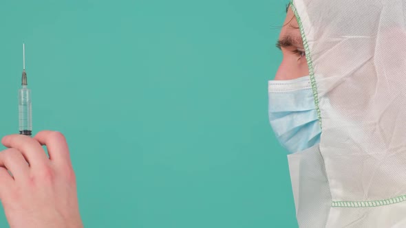 Side View of a Man in Protective Suit Staying Holding a Syringe with Vaccine alt