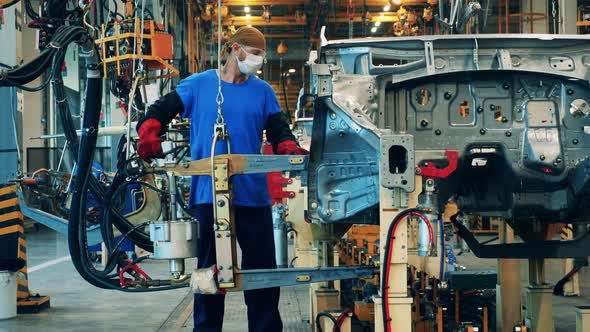 Car Manufacturing Worker Using a Welding Machine at a Car Factory alt