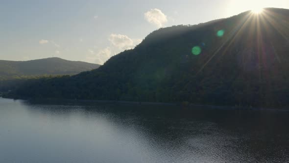 Aerial of bright sunlight over Breakneck Ridge on coast of Hudson river alt