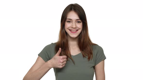 Portrait of Woman in Basic Wear Being Happy with Results and Gesturing Thumb Up on Camera with alt