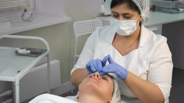 Cosmetologist Is Applying Yellow Peeling on Woman's Face Massaging Movements