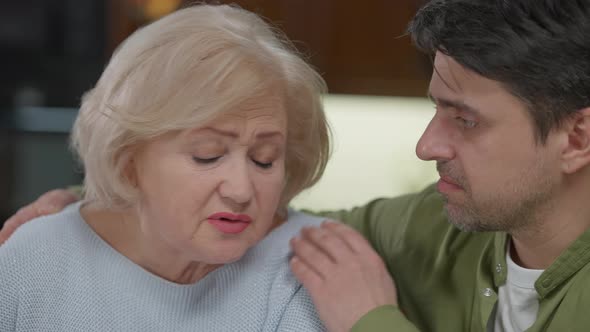 Closeup Stressed Senior Woman Grieving As Adult Man Talking Hugging Parent Supporting alt