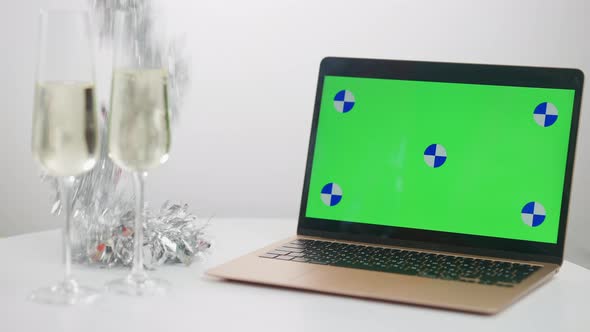 Chromakey Laptop and Two Champagne Glasses on Table with Sparkling Christmas Garland Lying Down at alt