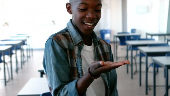Schoolboy looking at cupped hand in classroom alt
