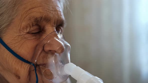 Close-up of an Old Woman with Closed Eyes Wearing a Medical Breathing Mask.